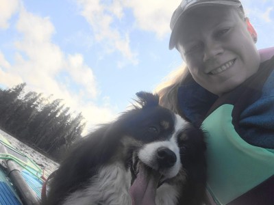 A girl and her dog floating on a paddleboard with the sky and shore line in the background
