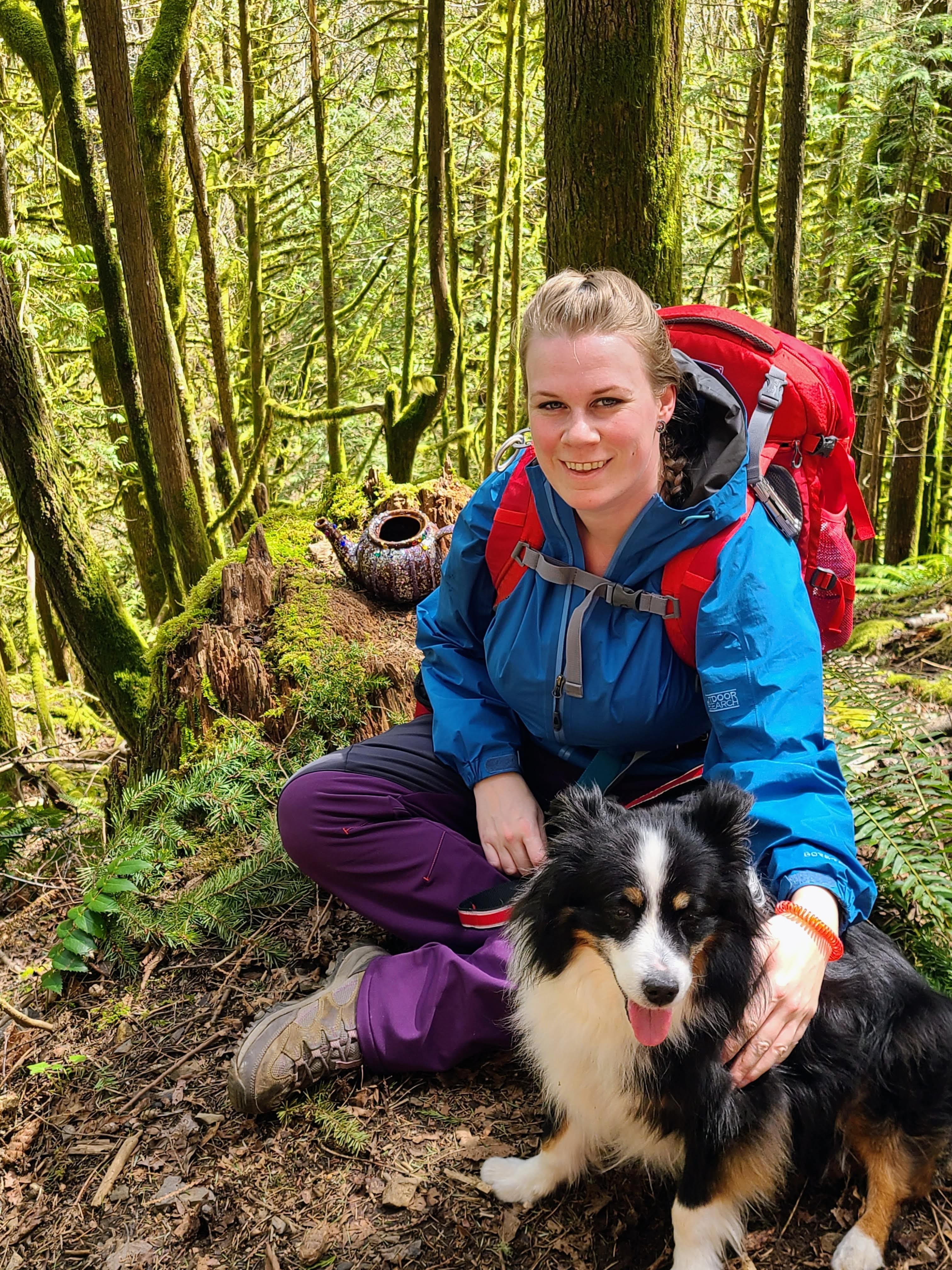 Girl and dog sit in the woods in front of a glitter teapot.