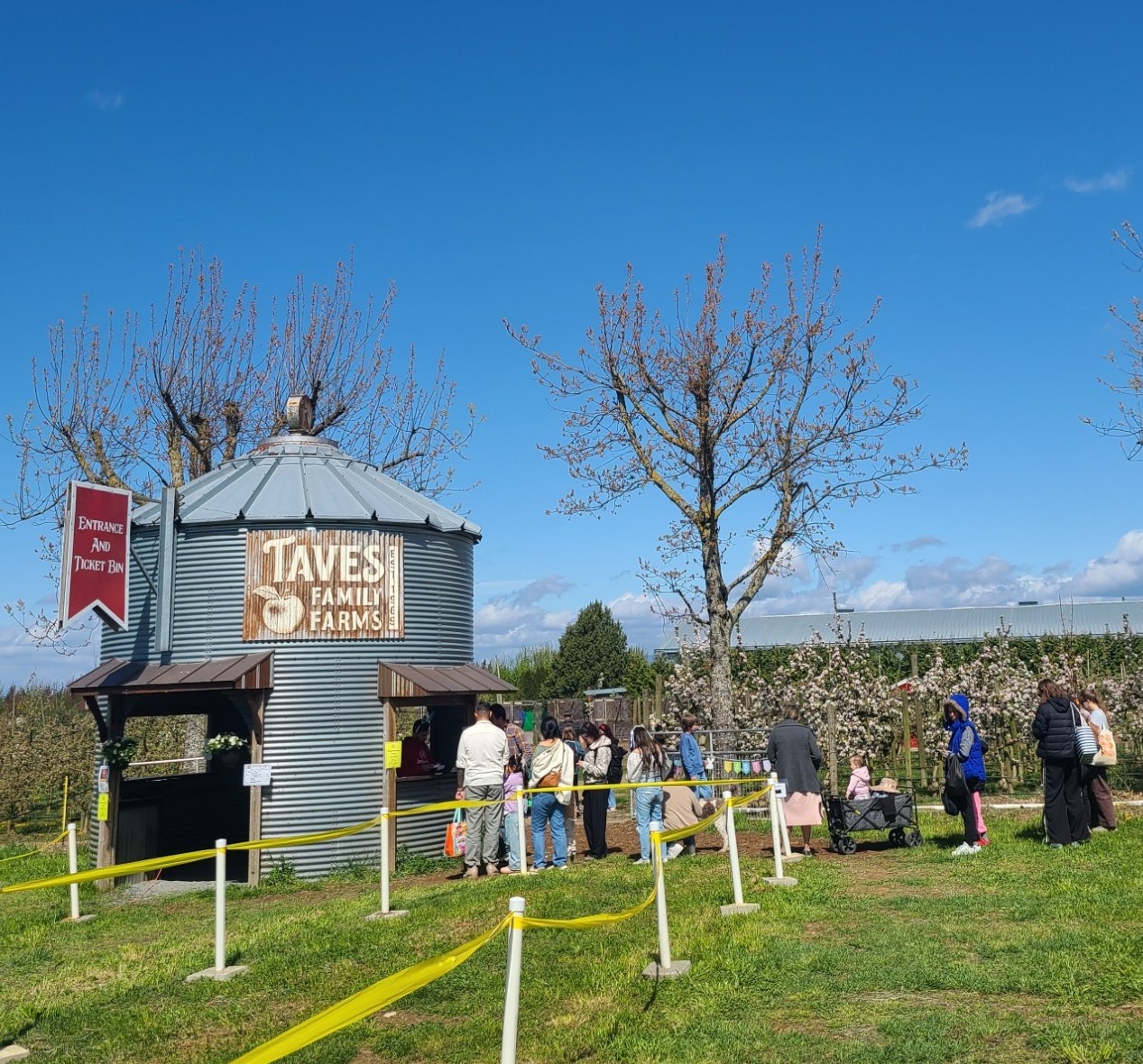 Entrance to farm with a large silo and people lined up for tickets.